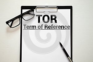 TOR. Terms Of Reference acronym on book. Office desk background