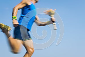 Torchbearer Athlete Running with Sport Torch Blue Sky photo