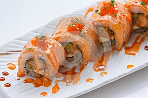 Torched Salmon Maki Sushi with Shrimp Tempura, Avocado and Cheese inside. Topping with Sauce, Ebiko Shrimp Egg and Scallion