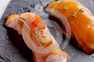Torched Salmon Sushi Topping with Cheese and Ebiko Shrimp Egg Served on Black Stone Plate.