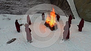 Torchlight procession. Ritual fire. Footage. Group of monks in hood robe walking along winter snow trail in forest