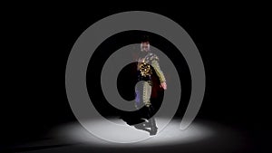 Torero in blue and gold suit or typical spanish bullfighter isolated spotlight on a black background. Close up, slow