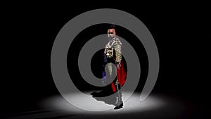 Torero in blue and gold suit or typical spanish bullfighter isolated spotlight on a black background. Close up, slow