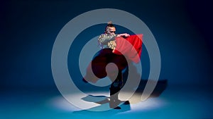 Torero in blue and gold suit or typical spanish bullfighter isolated spotlight on a blue background. Close up, slow