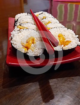 Tori Katsu Sushi at the red rectangular plate and red chopstick on it, at the table