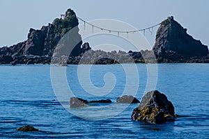Torii Gate and Shimenawa Rope on Shoreline Rocks