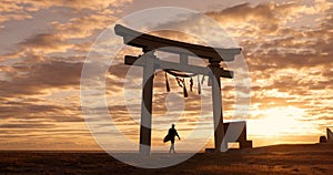 Torii gate, sunset and man at beach with surfboard, spiritual history and travel adventure in Japan. Shinto architecture