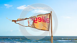 Torn beach flag and sea behind