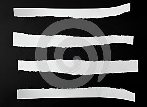torn blank white paper strips against a black background photo
