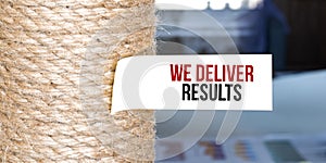 Torn brown paper on white surface with text WE DELIVER RESUTLS word