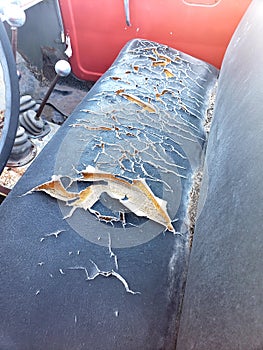 Torn dry cracked black bench seat to an old vehicle