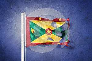 Torn flag of Grenada flying against grunge background