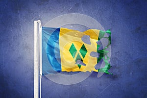 Torn flag of Saint Vincent and the Grenadines flying against grunge background photo