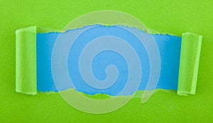 Torn green paper isolated on blue background