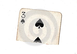 A torn half of a vintage three of spades playing card.