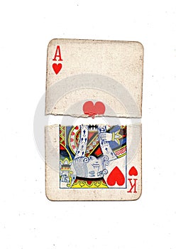 Torn halves of vintage playing cards showing an ace and king of hearts.