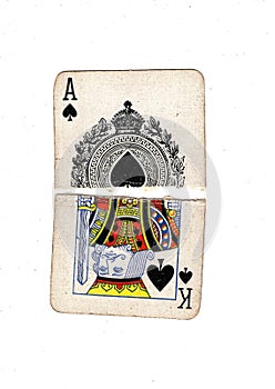 Torn halves of vintage playing cards showing an ace and king of spades.