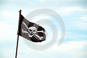 Torn Jolly Roger flies from flagpole