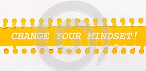 Torn paper strip on yellow background with text CHANGE YOUR MINDSET