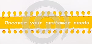 Torn paper strip on yellow background with text UNCOVER YOUR CUSTOMER NEEDS