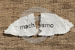 Torn paper written machismo, portuguese and spanish word for chauvism, over wood table. Concept of old and abandoned idea or photo