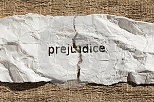 Torn paper written prejudice over wood table. Concept of old and