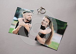 Torn photo of happy couple with rings on grey background. Concept of divorce