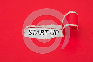 Torn red paper revealing the word start up concept.