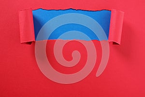 Torn red paper strip curled edge revealing top blue background space