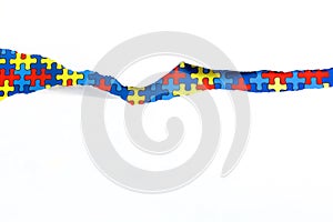 Torn white paper on multicolored puzzle background. Cocept for autism awareness day. Break barriers together for autism.