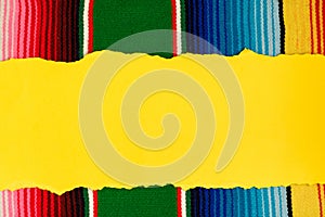 Torn yellow paper on colorful serape. Empty template for text