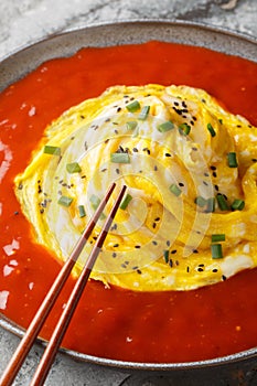 Tornado omurice omelet omelette with rice and hot sauce closeup on the plate. Vertical