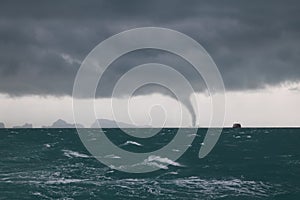 Tornado and storm cloud in the sea while the ship is sailing