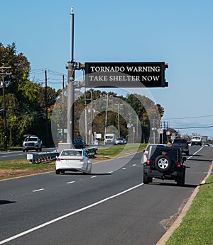 Tornado warning take shelter now, electronic warning sign over highway