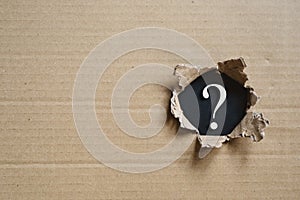 Torned corrugated box revealing question mark.
