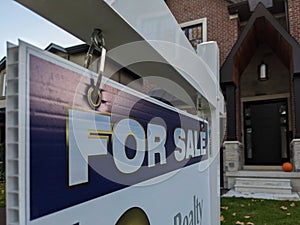 Sign for sale in front of a detached house in residential area.