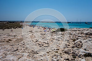 Torquoise color of the water with white sand in sunny day the Ses Illetes beach full of people