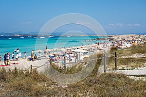 Torquoise color of the water with white sand in sunny day the Ses Illetes beach full of people