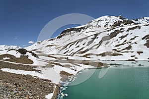 Torquoise lake in high altitude mountains with ice cakes