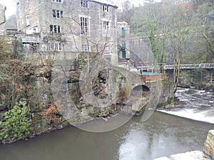 Torr Vale Mill with the Goyt river in the foreground in Torrs Riverside Park, New Mills