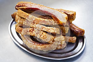 Plate of Torreznos on a metallic plate on a grey kitchen background.