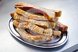 Plate of Torreznos on a metallic plate on a grey kitchen background.