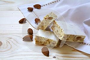 Torrone or white nougat with almonds and napkin on a wooden tab