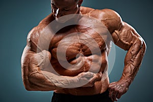 Torso of attractive male body builder on gray background.