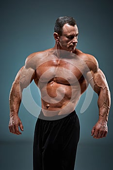 Torso of attractive male body builder on gray background.