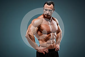 Torso of attractive male body builder on gray background.