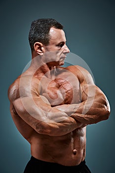 Torso of attractive male body builder on gray background.