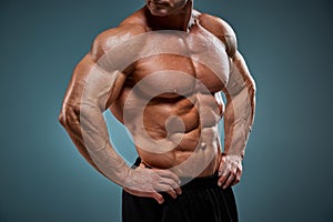 Torso of attractive male body builder on gray background.