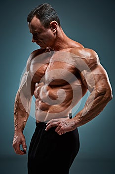 Torso of attractive male body builder on gray background.