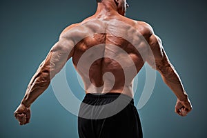 Torso of attractive male body builder on gray background.